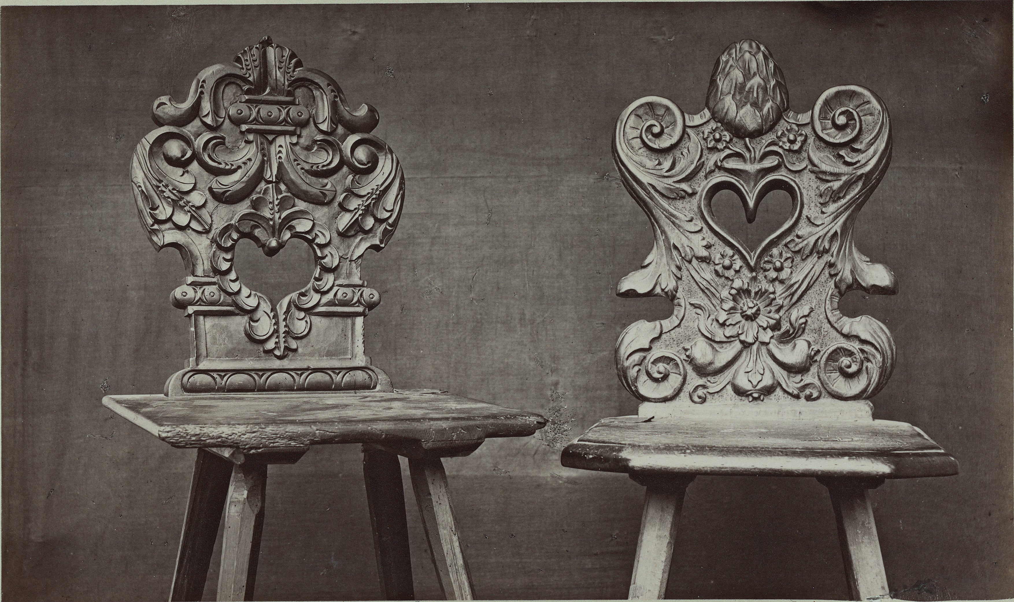 Two ornate chairs with intricate designs on a dark background