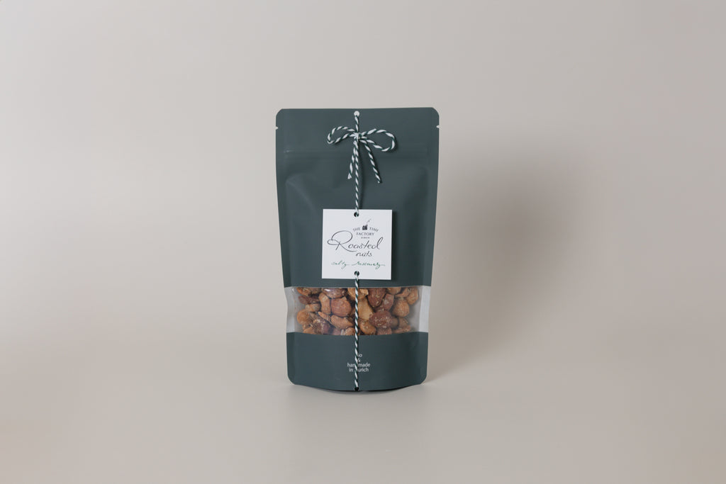 Dark green packaging of roasted nuts with a label on a light gray background