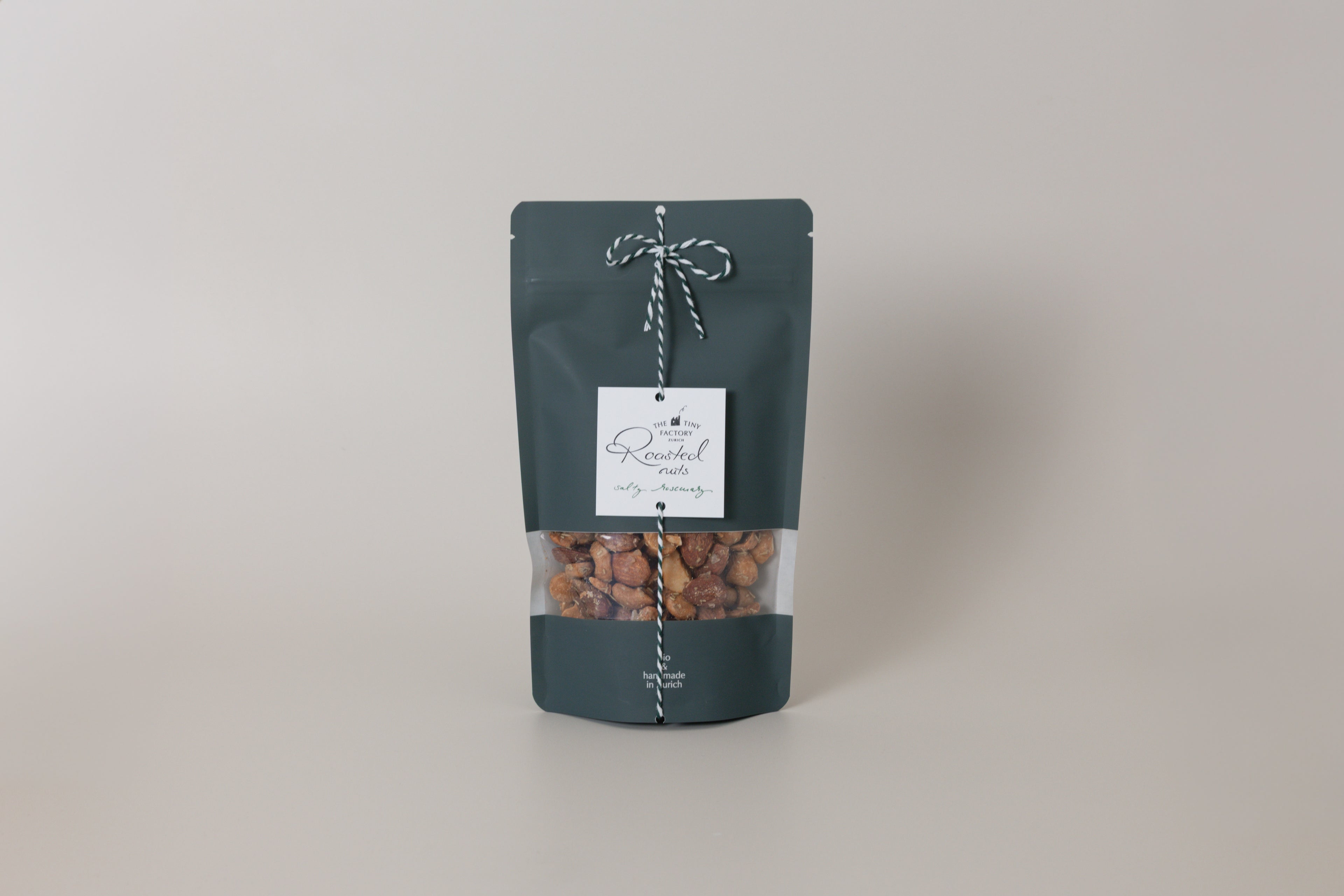 Dark green packaging of roasted nuts with a label on a light gray background