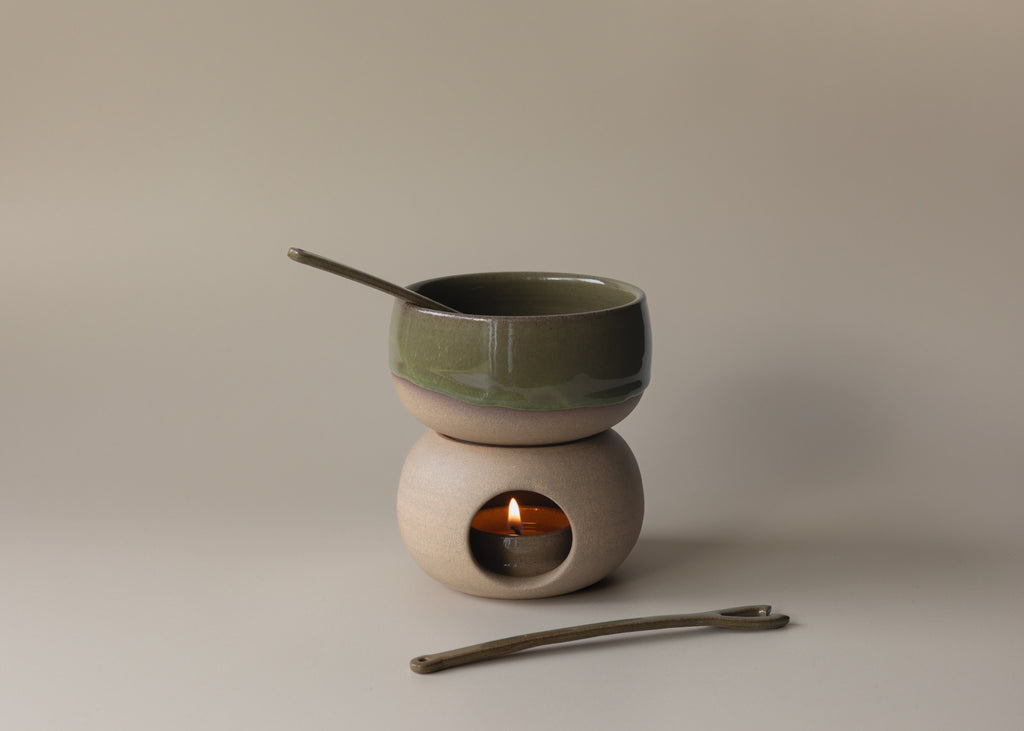 Ceramic tea light warmer with a small bowl on top and a candle inside, on a neutral background.
