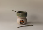 Ceramic tea light warmer with a small bowl on top and a candle inside, on a neutral background.