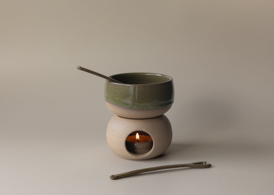 Ceramic tea light warmer with a small bowl on top and a candle inside, on a neutral background.