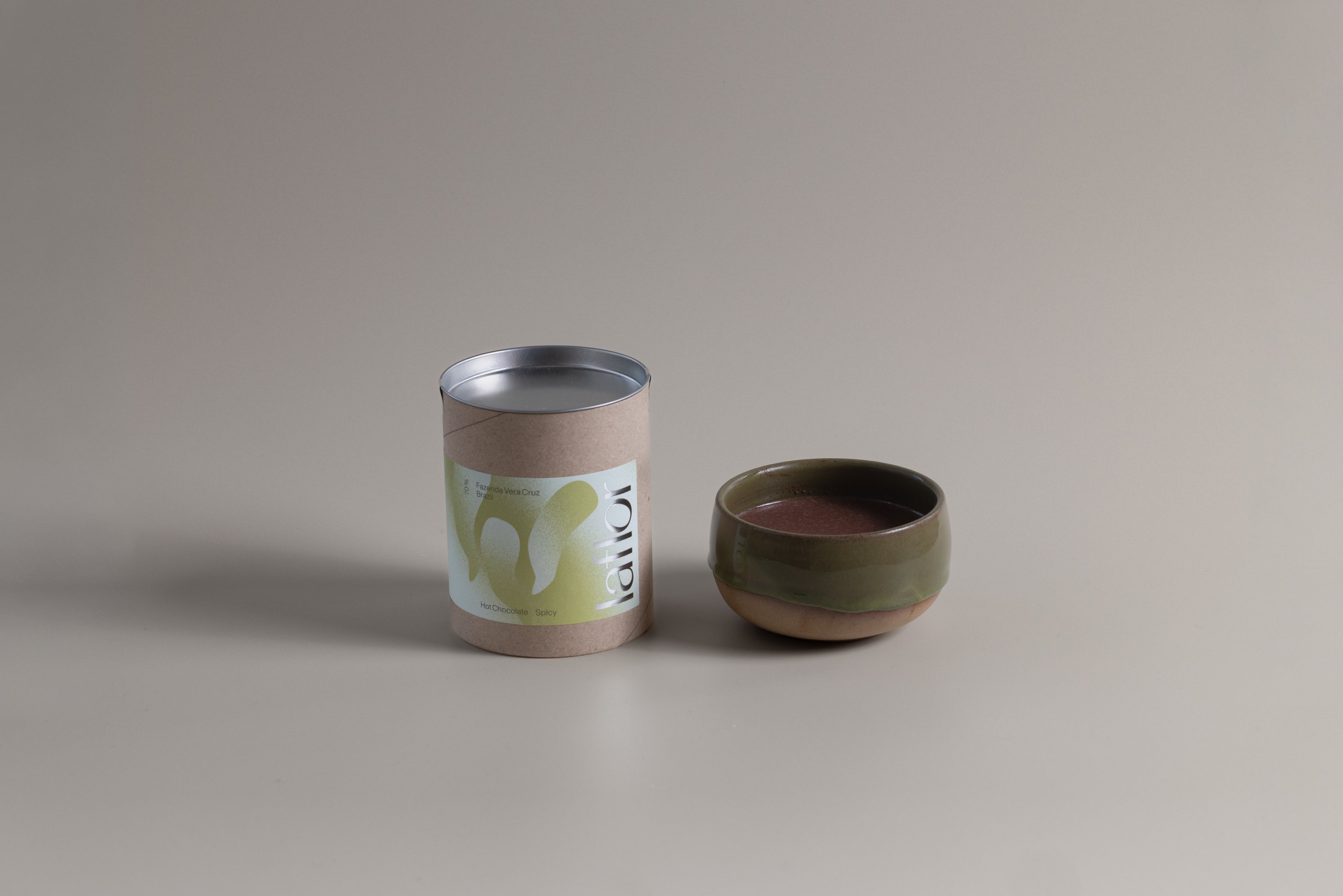 Ceramic cup and cylindrical container with label on a beige background