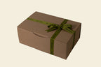 Brown gift box with a green ribbon on a light gray background