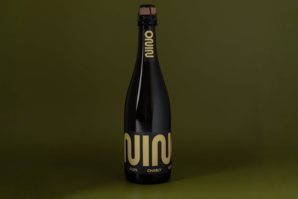 Black nino alcool free bottle with gold label on a green background