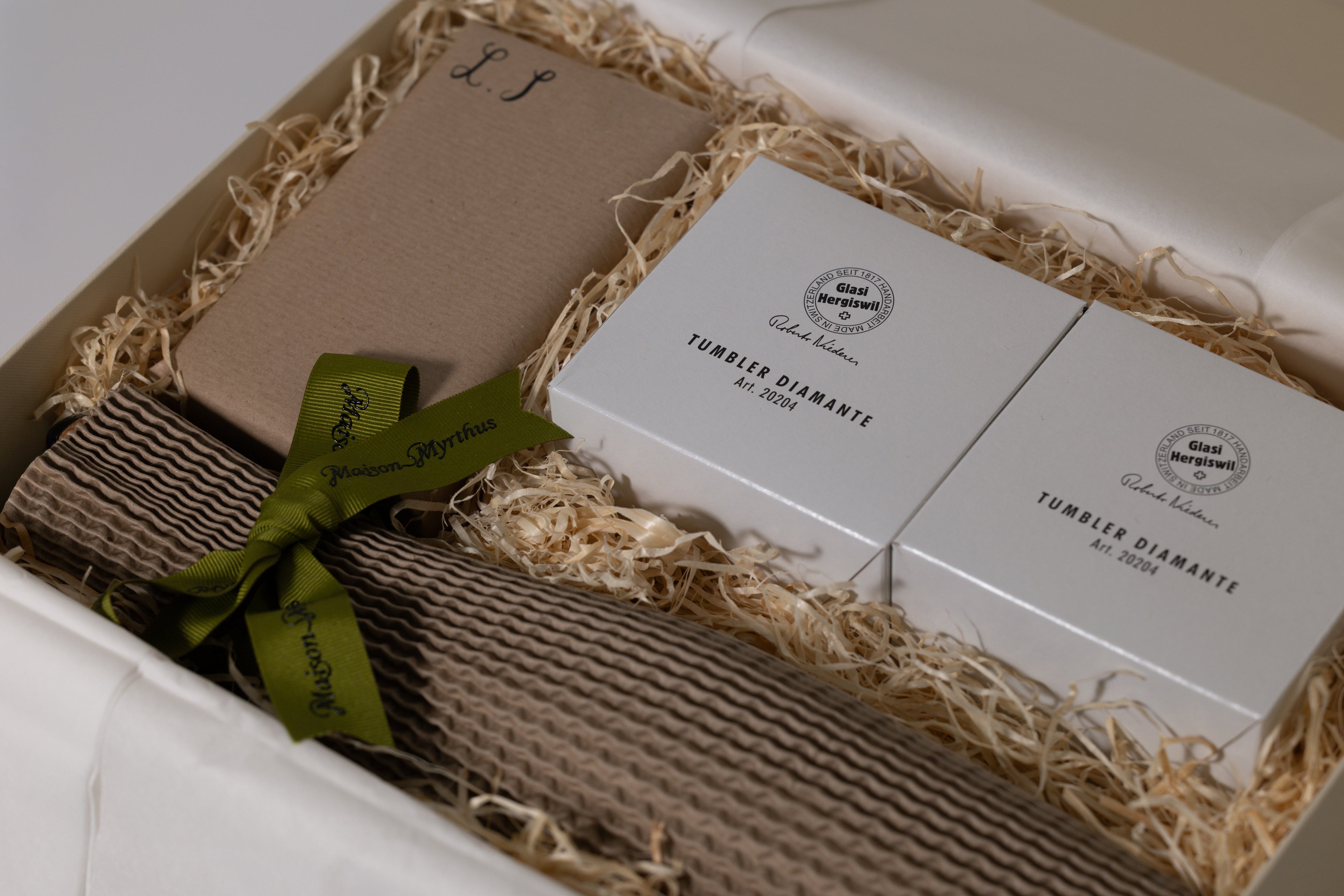 Gift box with two white boxes labeled 'Tumbler Diamond' and brown paper, tied with a green ribbon.