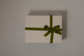 beige gift box with a green ribbon on a gray background