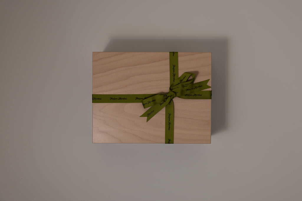Wooden boxwith a green ribbon on a gray background
